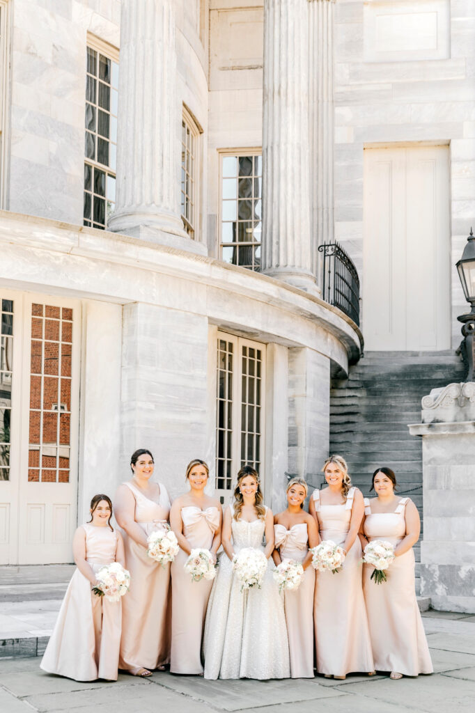 Philadelphia bride with her bridesmaids in pink satin bridesmaid dresses at Merchant's Exchange