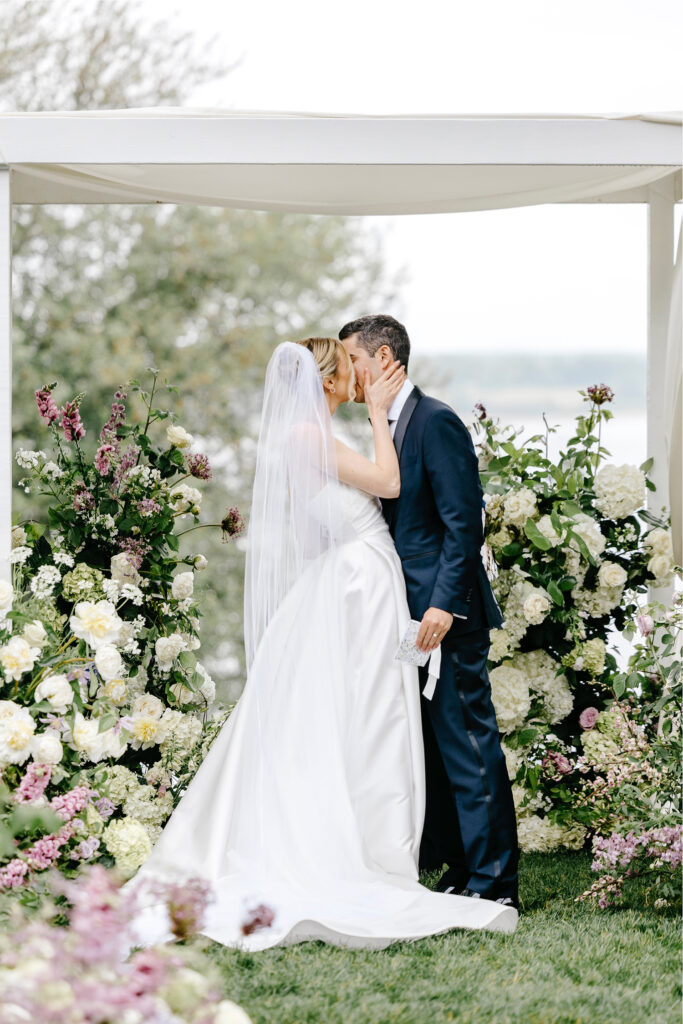 bride & grooms first kiss at their garden wedding ceremony by the river
