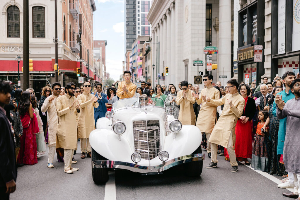Philadelphia groom arriving to wedding street party on Chestnut St. in a white convertible