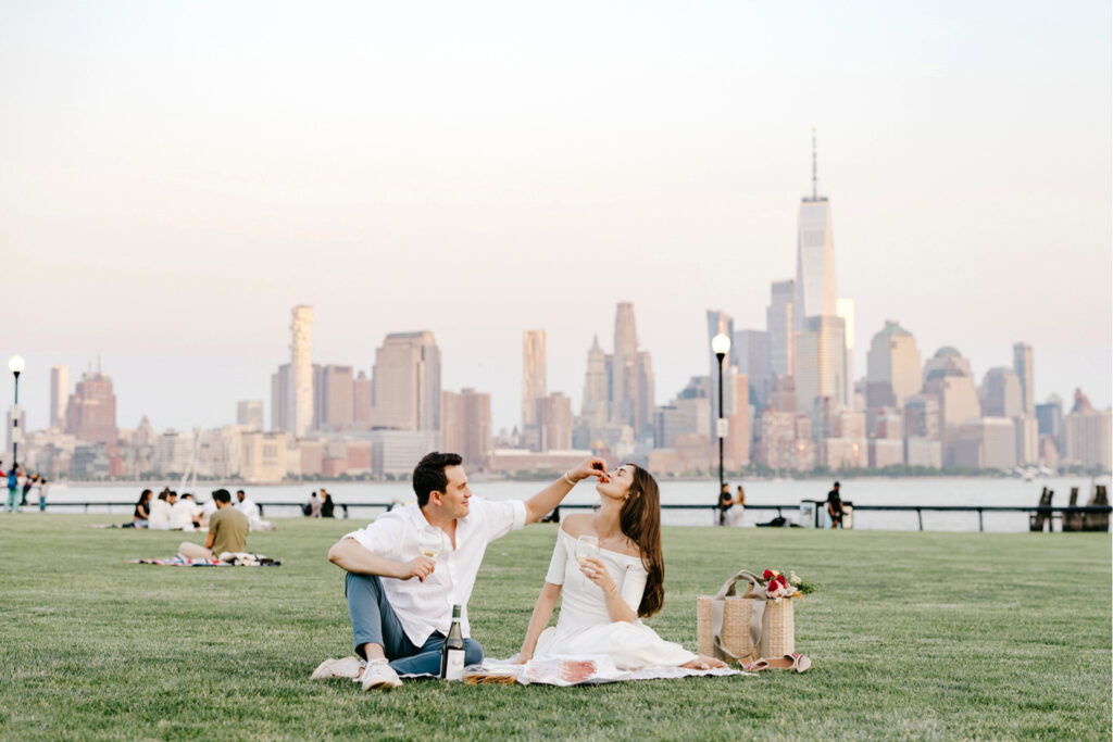 Hoboken couple having a romantic couple at Pier A Park with the Manhattan Skyline in the background
