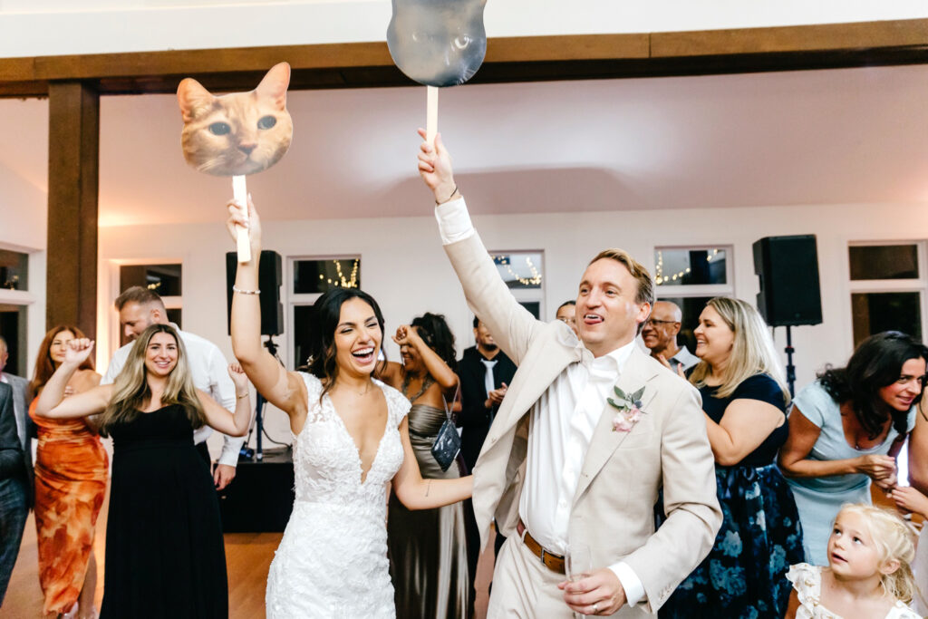 bride & groom enjoying their summer wedding reception holding cut-outs of their pets heads