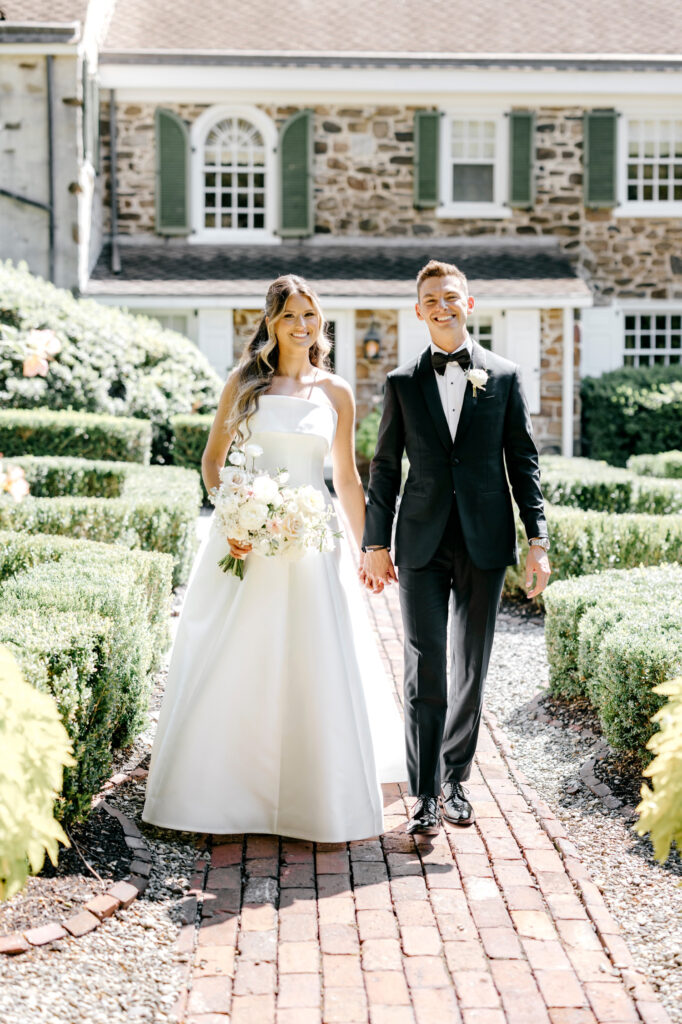 Pennsylvania bride and groom walking hand in hand along the gardens of Appleford Estate by Emily Wren Photography