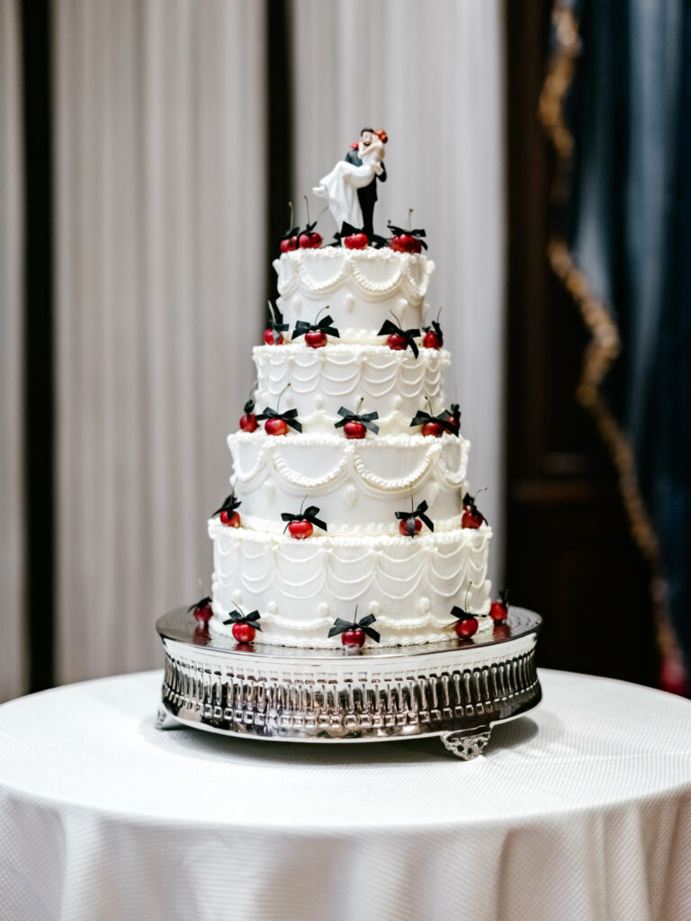 four tier vintage-inspired wedding cake with cherries and bows decorated by Emily Wren Photography