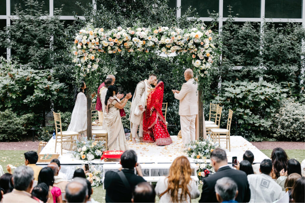 Philadelphia bride and groom's first kiss at their outdoor Hindu Western wedding ceremony