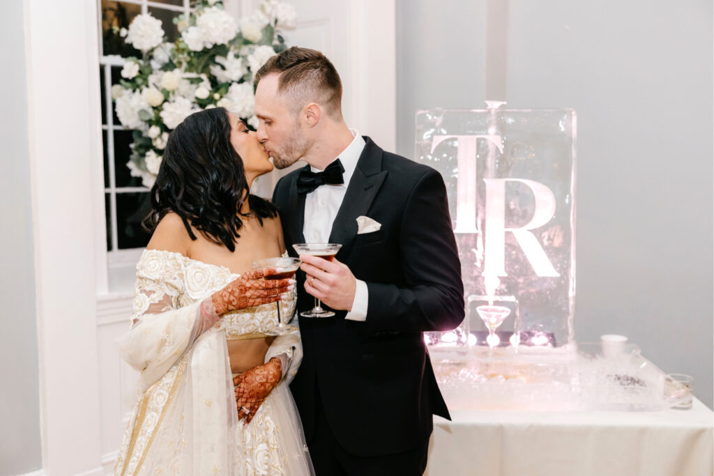 Philadelphia bride and groom in front of their ice sculpture carved with their initials at their Cescaphe cocktail hour