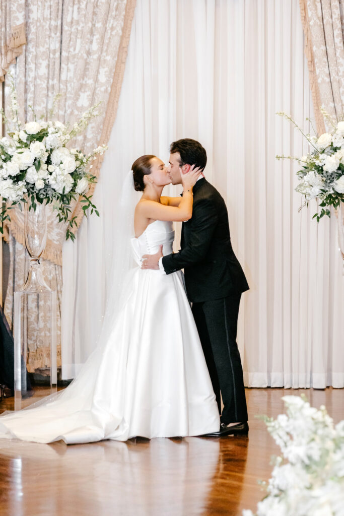 bride and groom's first kiss at their glamorous Hotel Du Pont wedding ceremony by Emily Wren Photography