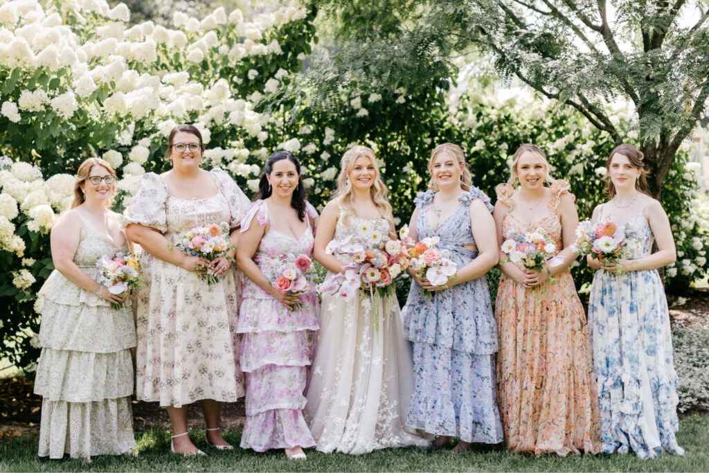 New Hampshire bride with her bridesmaids in colorful pastel floral bridesmaid dresses by Emily Wren Photography
