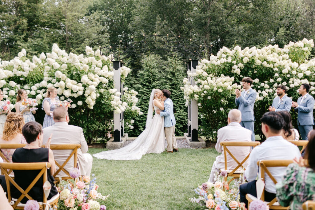 New Hampshire bride and groom's first kiss at their outdoor summer wedding ceremony at Uncanoonuc Mountain