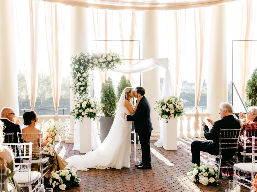 bride and groom's first kiss at their all white wedding ceremony at Philadelphia Water Works