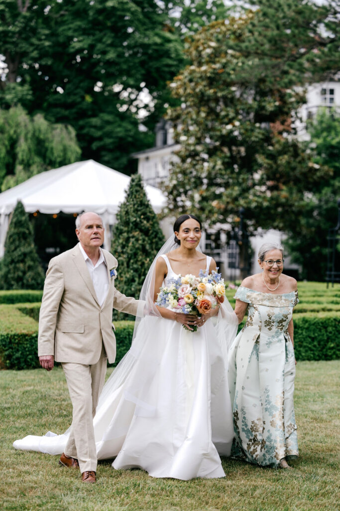 Philadelphia bride walking down the aisle at her outdoor wedding ceremony with both of her parents by Emily Wren Photography
